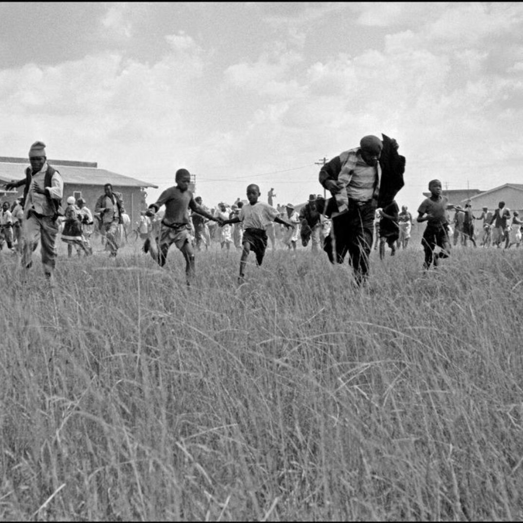 SOUTH AFRICA.  Transvaal.  Sharpeville.  Villagers flee the centre of the village where the police have opened fire on them, trying to protect themselves from the bullets by putting their coats over their head. 1960.